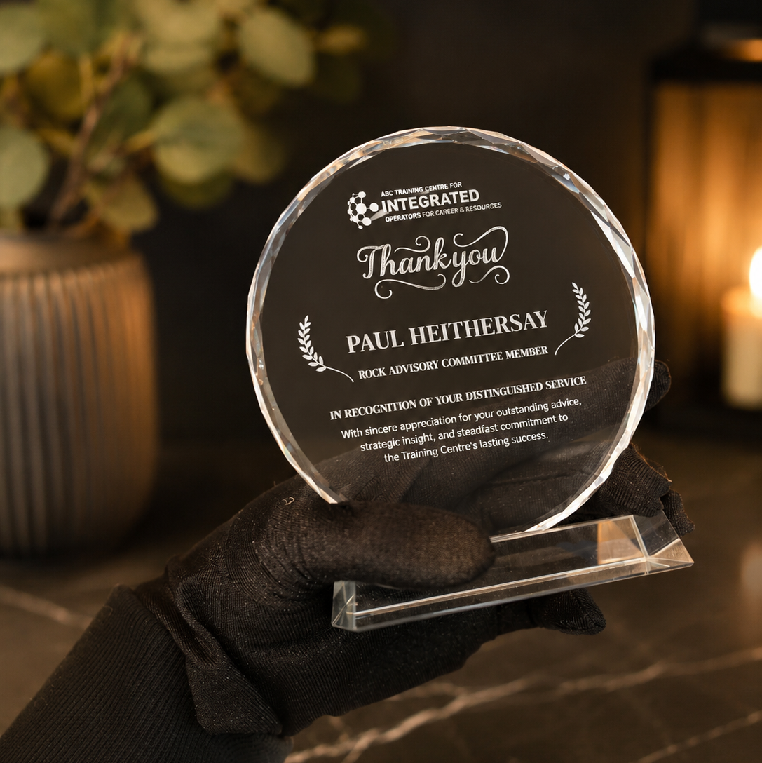 A clear crystal glass round thank-you award plaque with engraved text
