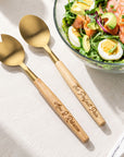 Personalised engraved acacia wood and gold salad servers beside a salad bowl