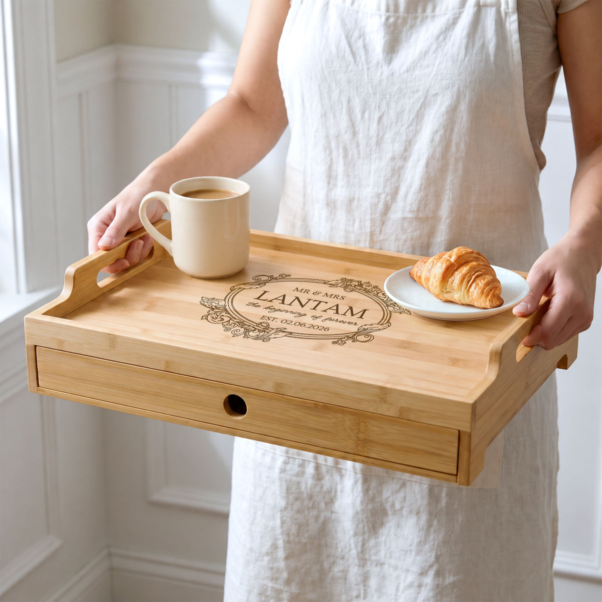 Personalised bamboo serving tray with a centre engraving being carried by the handles