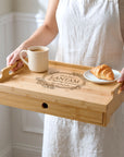 Personalised bamboo serving tray with a centre engraving being carried by the handles