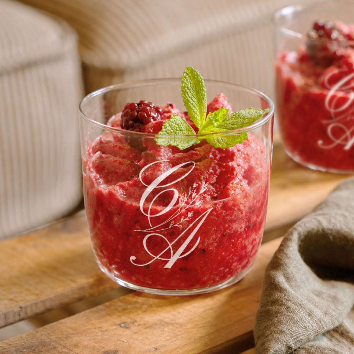 Personalised engraved glass tumbler with a monogram holding a berry dessert