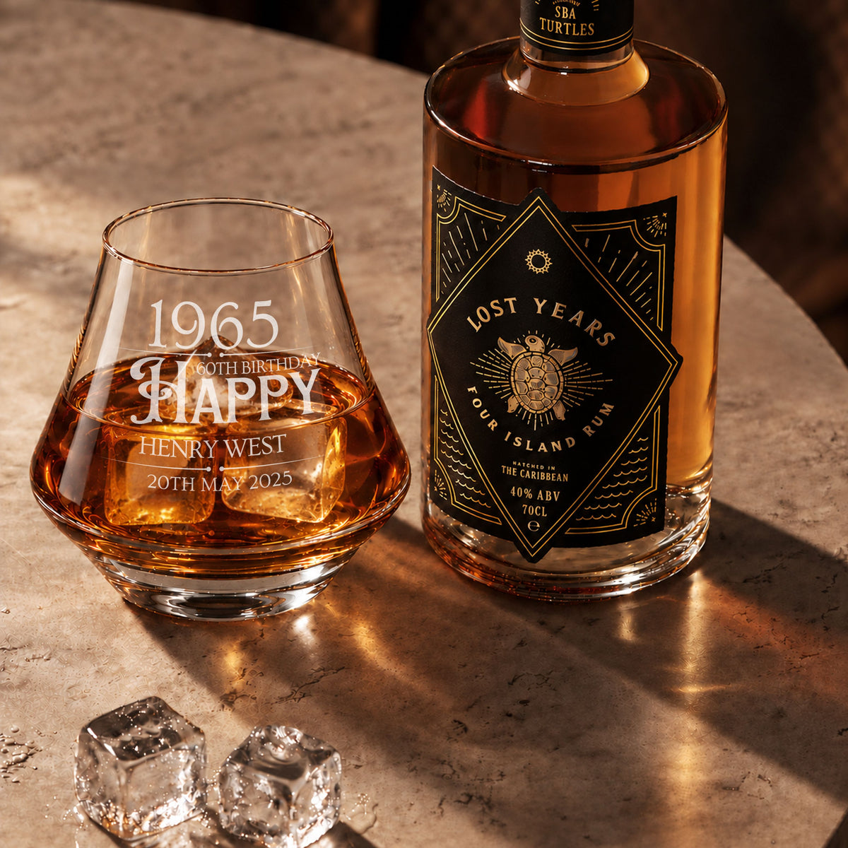 Personalised engraved whisky glass with a birthday design beside a bottle of rum