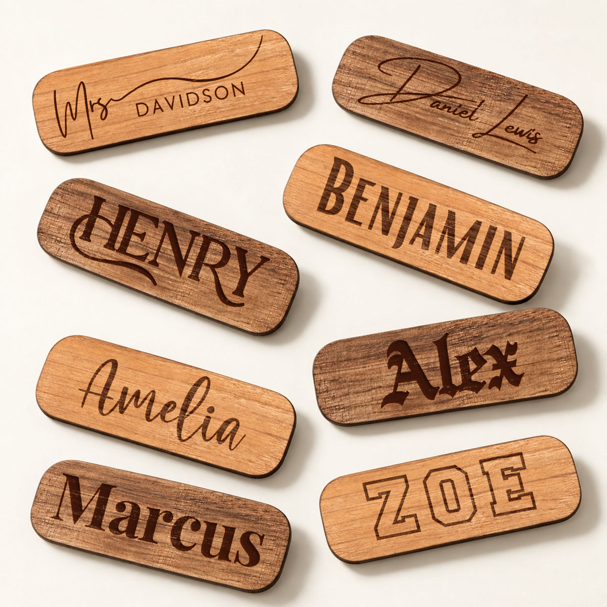 Oval wooden name badges engraved with names in a range of fonts