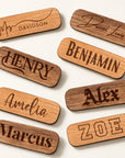 Oval wooden name badges engraved with names in a range of fonts