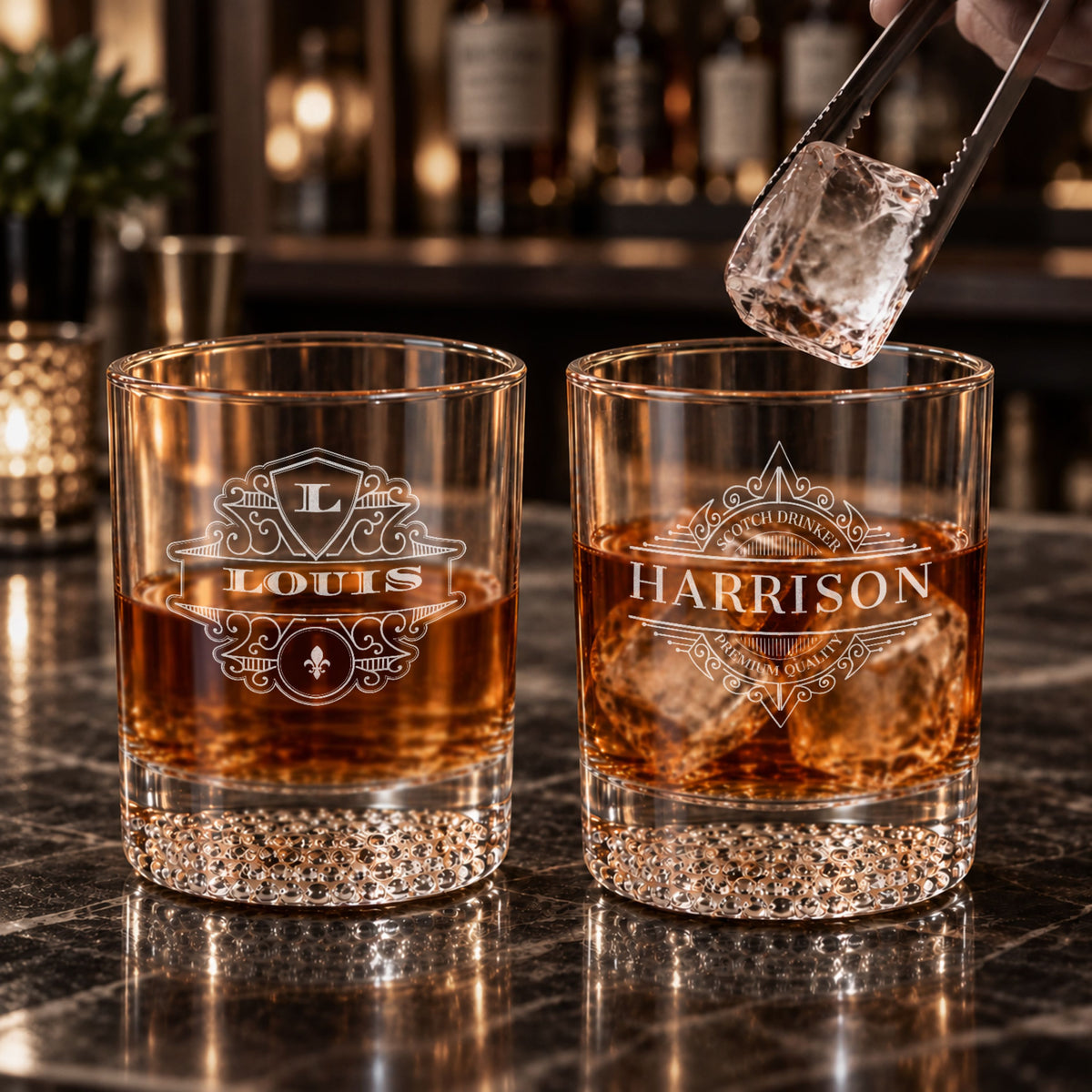 Pair of personalised patterned-bottom whisky tumblers engraved with names on a bar