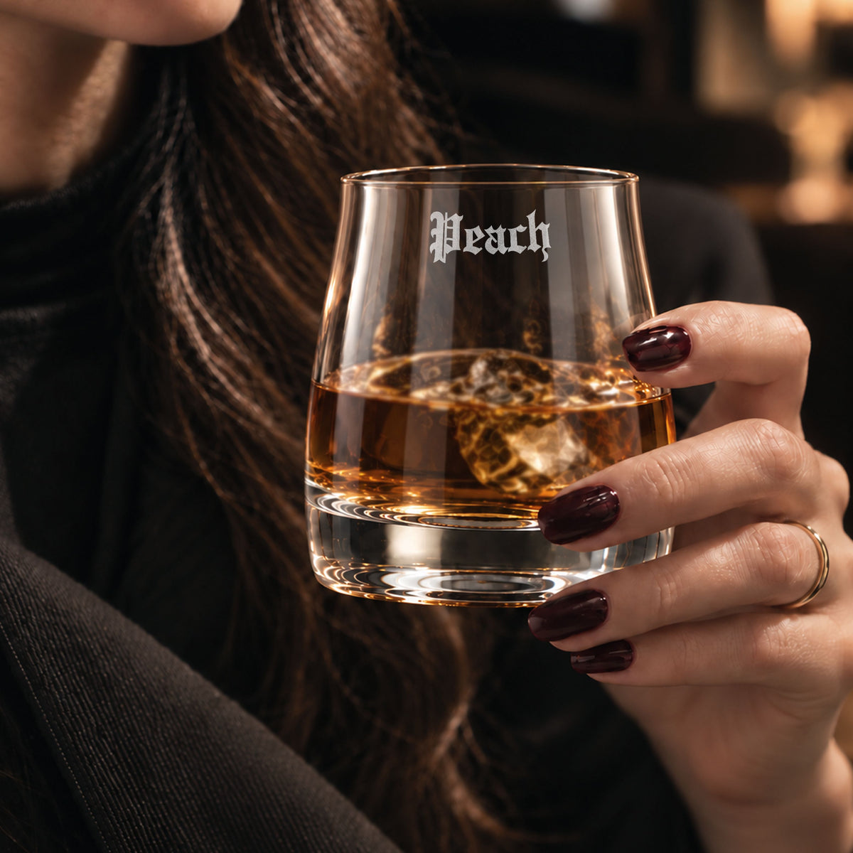 Personalised rocks whisky glass engraved with a name, held with whisky