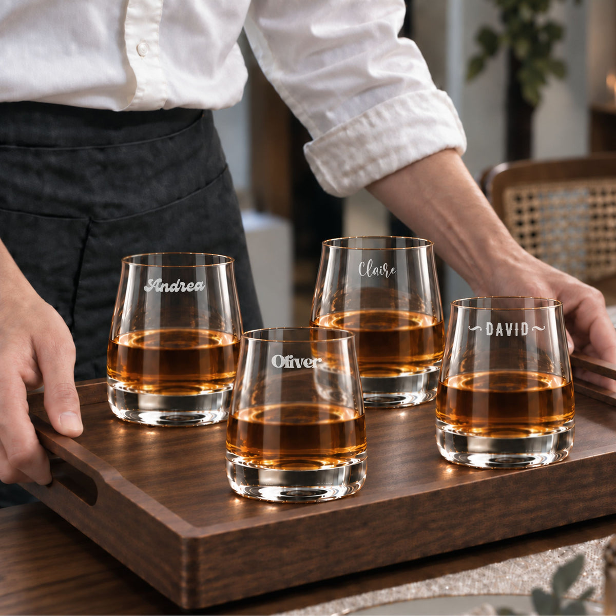 Set of four personalised rocks whisky glasses engraved with names on a serving tray