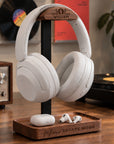 Personalised walnut and metal headphone stand with engraved head and storage tray holding AirPods