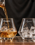 Pair of personalised whisky glasses engraved with names, whisky being poured