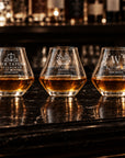 Three personalised engraved whisky tumblers on a bar with whisky